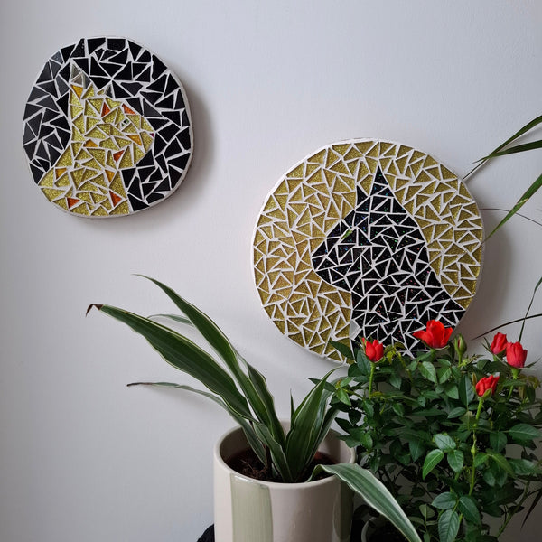 Cat mosaics on the wall surrounded by plants
