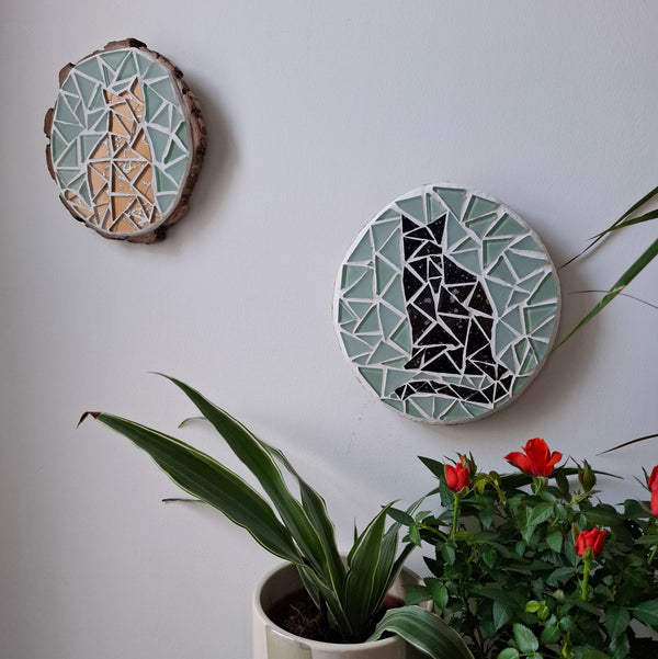 Cat mosaics on the wall surrounded by plants