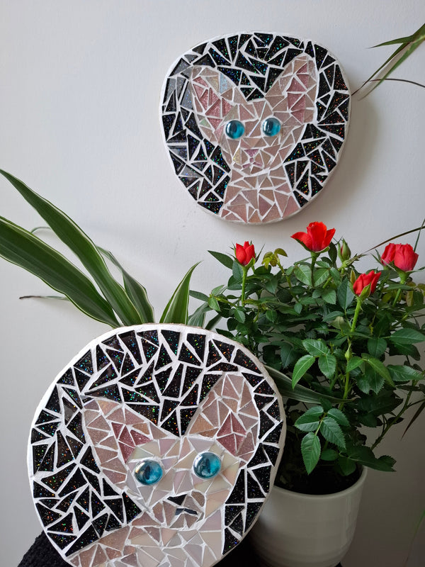 Cat mosaics on the wall surrounded by plants
