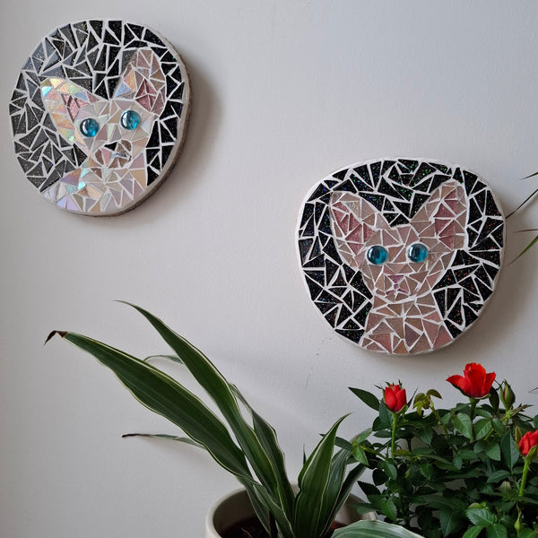 Cat mosaics on the wall surrounded by plants
