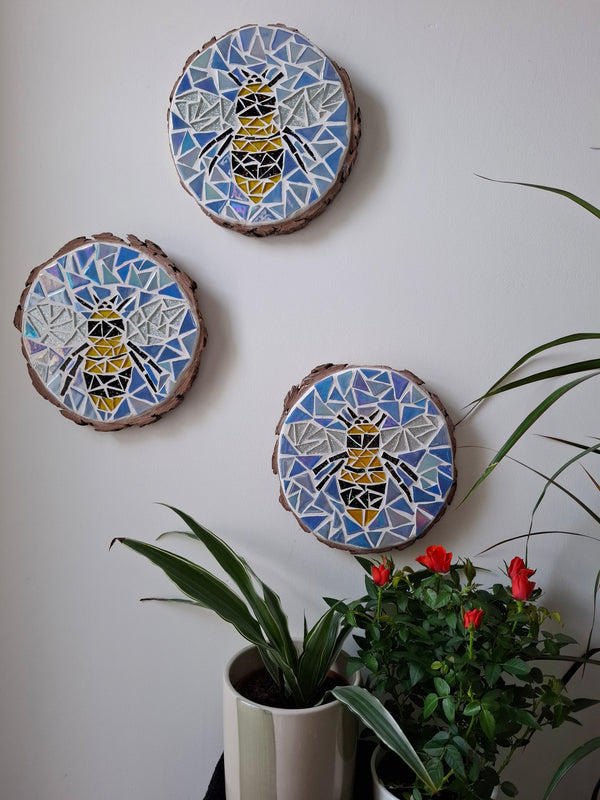 Bee mosaics on the wall surrounded by plants
