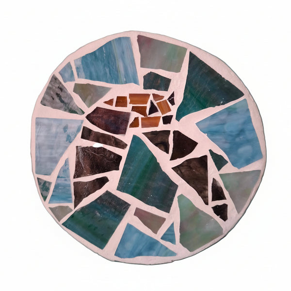Circular mosaic wall art featuring a stylized bat design. Crafted with black and brown stained glass pieces on a blue and green background, set on rustic wood.