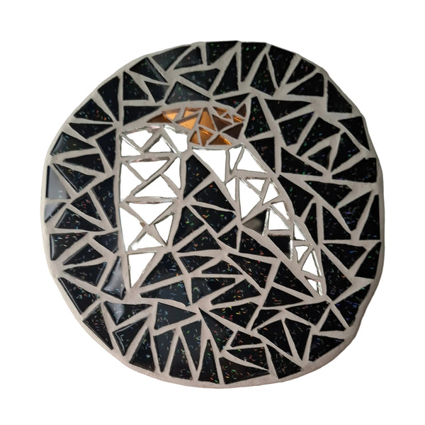 Circular mosaic wall art featuring a stylized bat design. Crafted with reflective silver and bronze glass mirror pieces on a sparkly black background, set on rustic wood.
