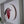 A circular stained-glass-style robin wall art piece mounted inside a white shadow box frame. The bird design features red, black, white, and brown sections, with a natural wood slice edge visible on the right side.