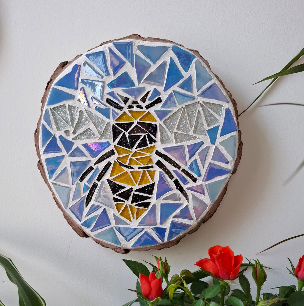 Bee mosaic on the wall surrounded by plants
