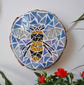 Bee mosaic on the wall surrounded by plants
