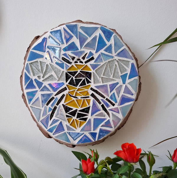 Bee mosaic on the wall surrounded by plants
