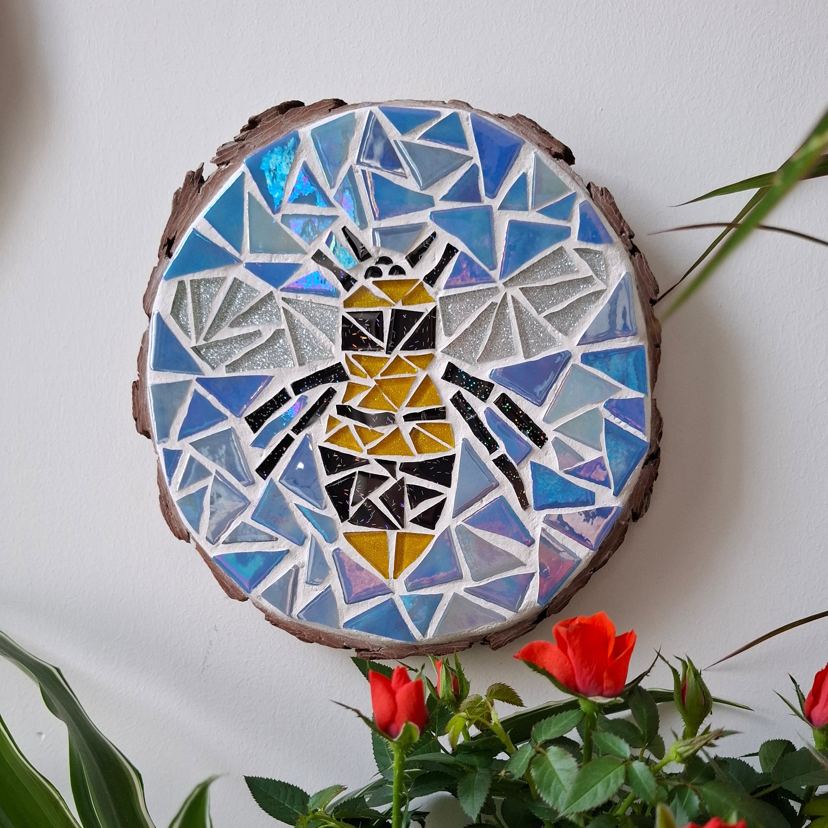 Bee mosaic on the wall surrounded by plants
