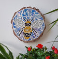 Bee mosaic on the wall surrounded by plants
