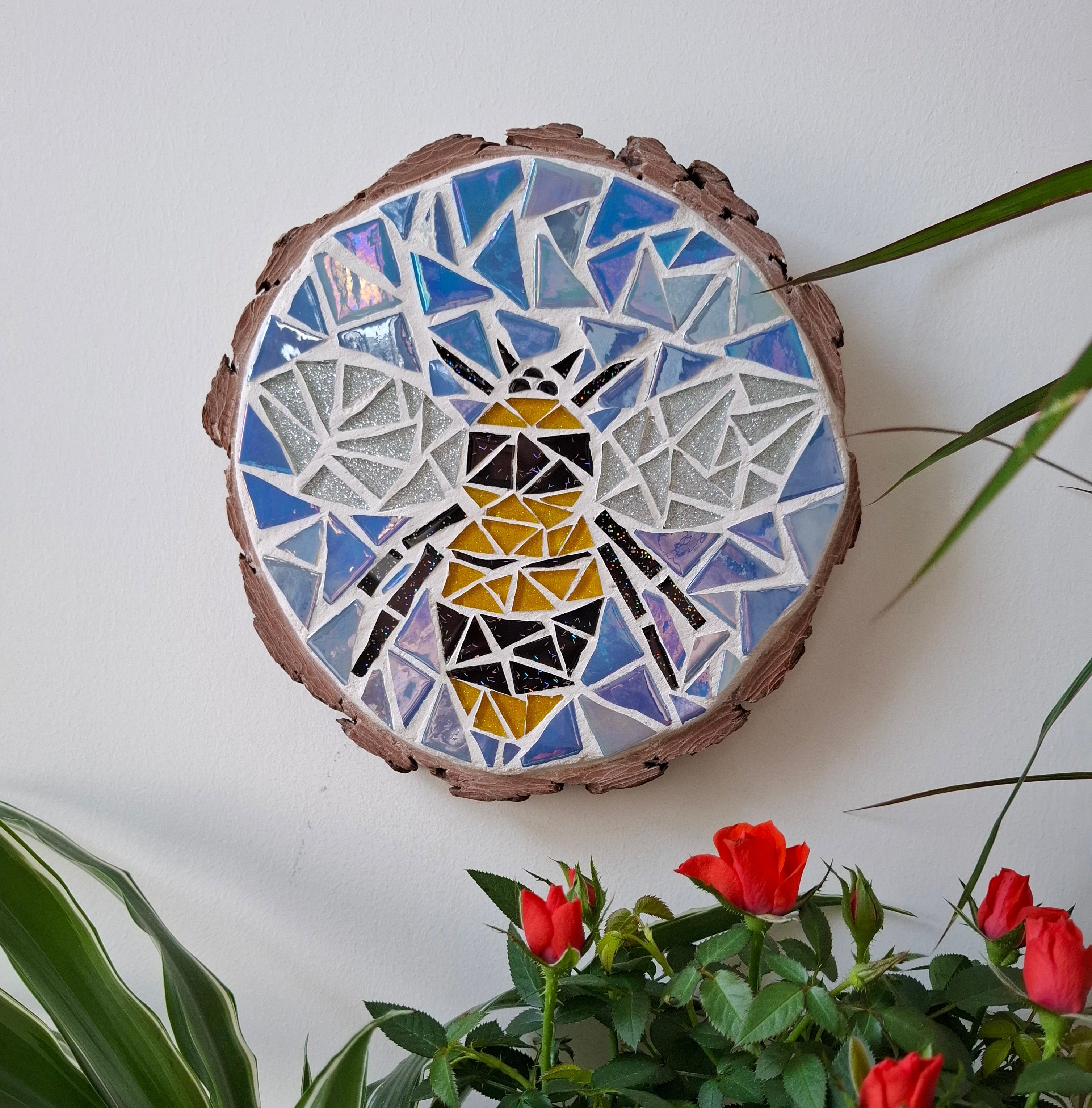 Bee mosaic on the wall surrounded by plants
