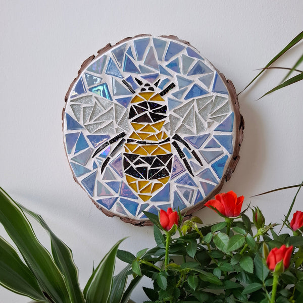 Bee mosaic on the wall surrounded by plants
