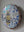 Side view of a circular bee mosaic artwork, showing the rustic wood edge.