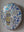 Side view of a circular bee mosaic artwork, showing the rustic wood edge.
