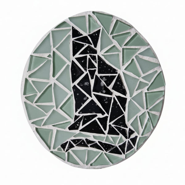 Circular mosaic wall art featuring a stylized cat silhouette design. Crafted with glittery black glass pieces on a frosted aqua background, set on rustic wood.