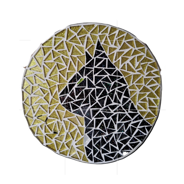 Circular mosaic wall art featuring a stylized cat design. Crafted with glittery black glass pieces on glittery gold background, set on rustic wood.