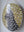 Side view of a circular cat mosaic artwork, showing the rustic wood edge.