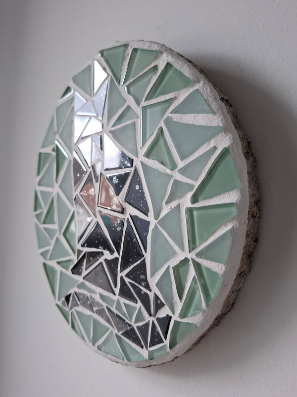 Side view of a circular cat mosaic artwork, showing the rustic wood edge.