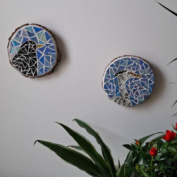 Bird mosaics on the wall surrounded by plants
