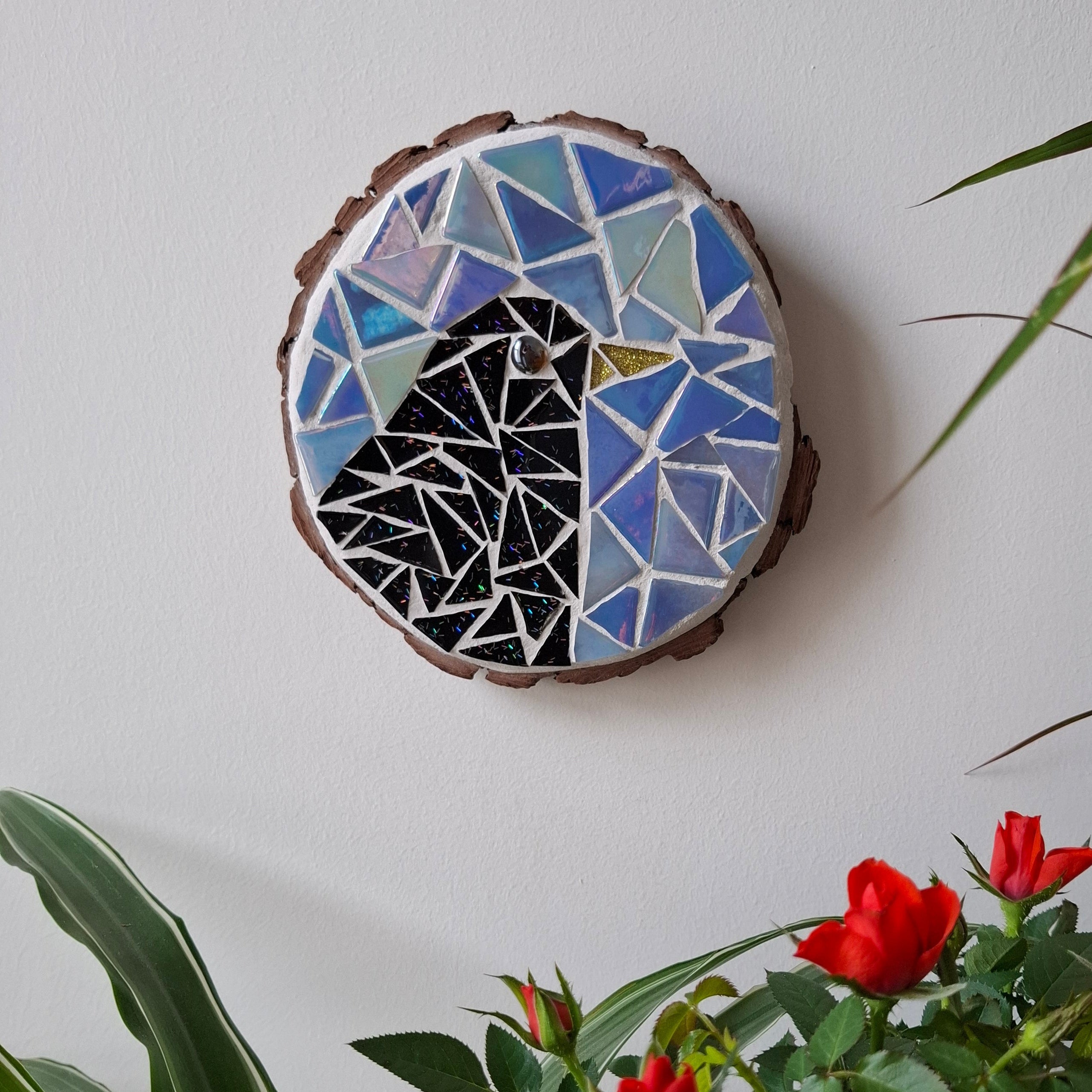 Bird mosaic on the wall surrounded by plants
