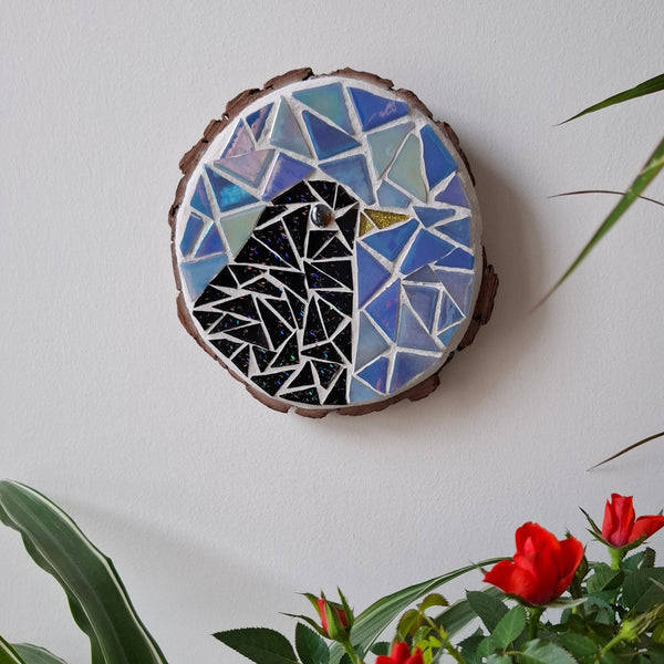 Bird mosaic on the wall surrounded by plants

