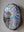 Side view of a circular bird mosaic artwork, showing the rustic wood edge.