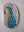 Side view of a circular macaw mosaic artwork, showing the rustic wood edge.