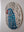 Side view of a circular parakeet mosaic artwork, showing the rustic wood edge.