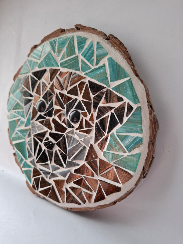 Side view of a circular dog mosaic artwork, showing the rustic wood edge.