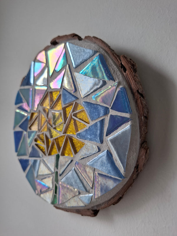 Side view of a circular flower mosaic artwork, showing the rustic wood edge.