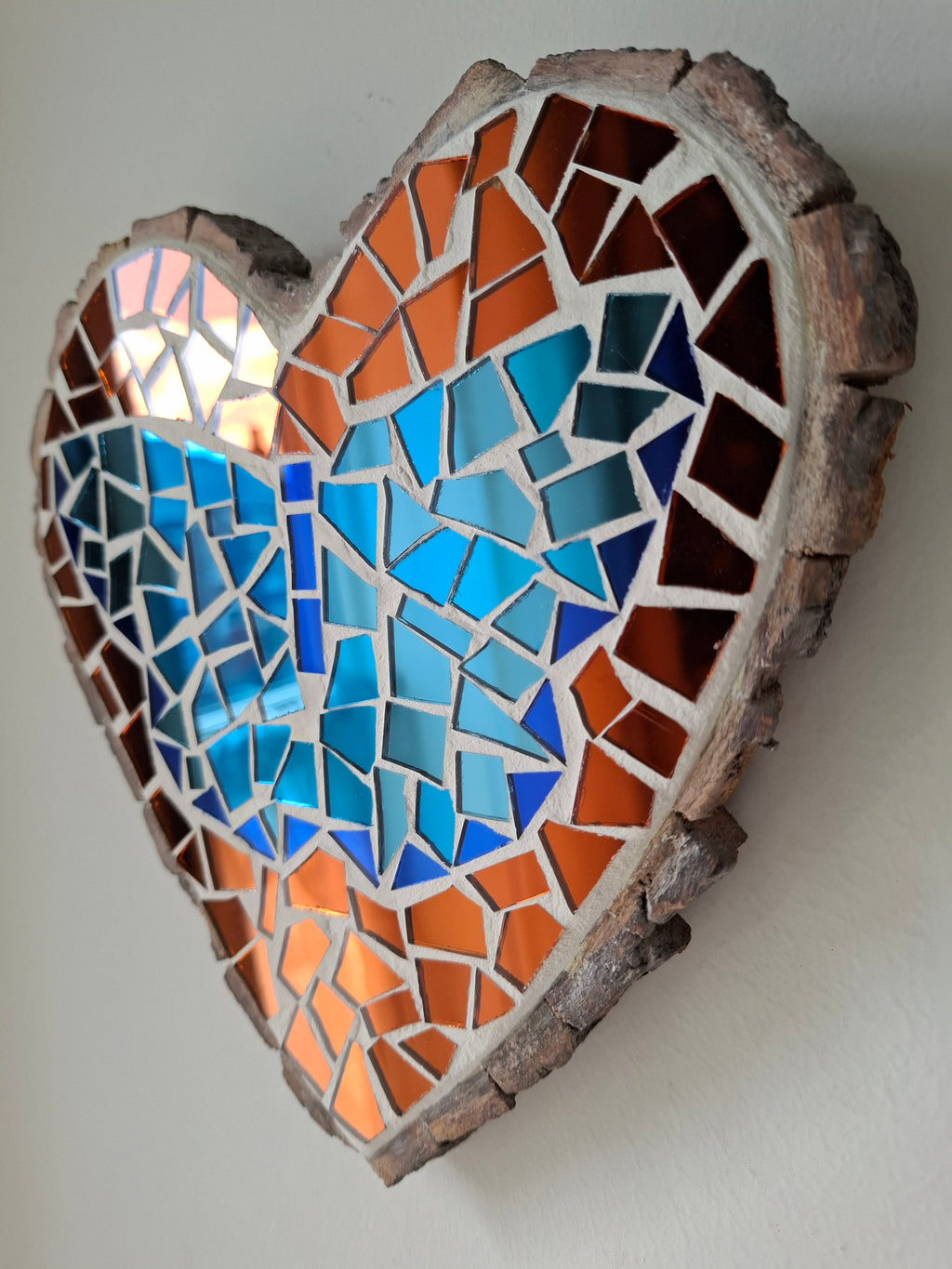 Side view of a heart shaped butterfly mosaic artwork, showing the rustic wood edge.