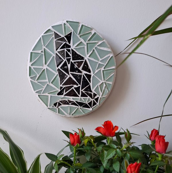 Cat mosaic on the wall surrounded by plants