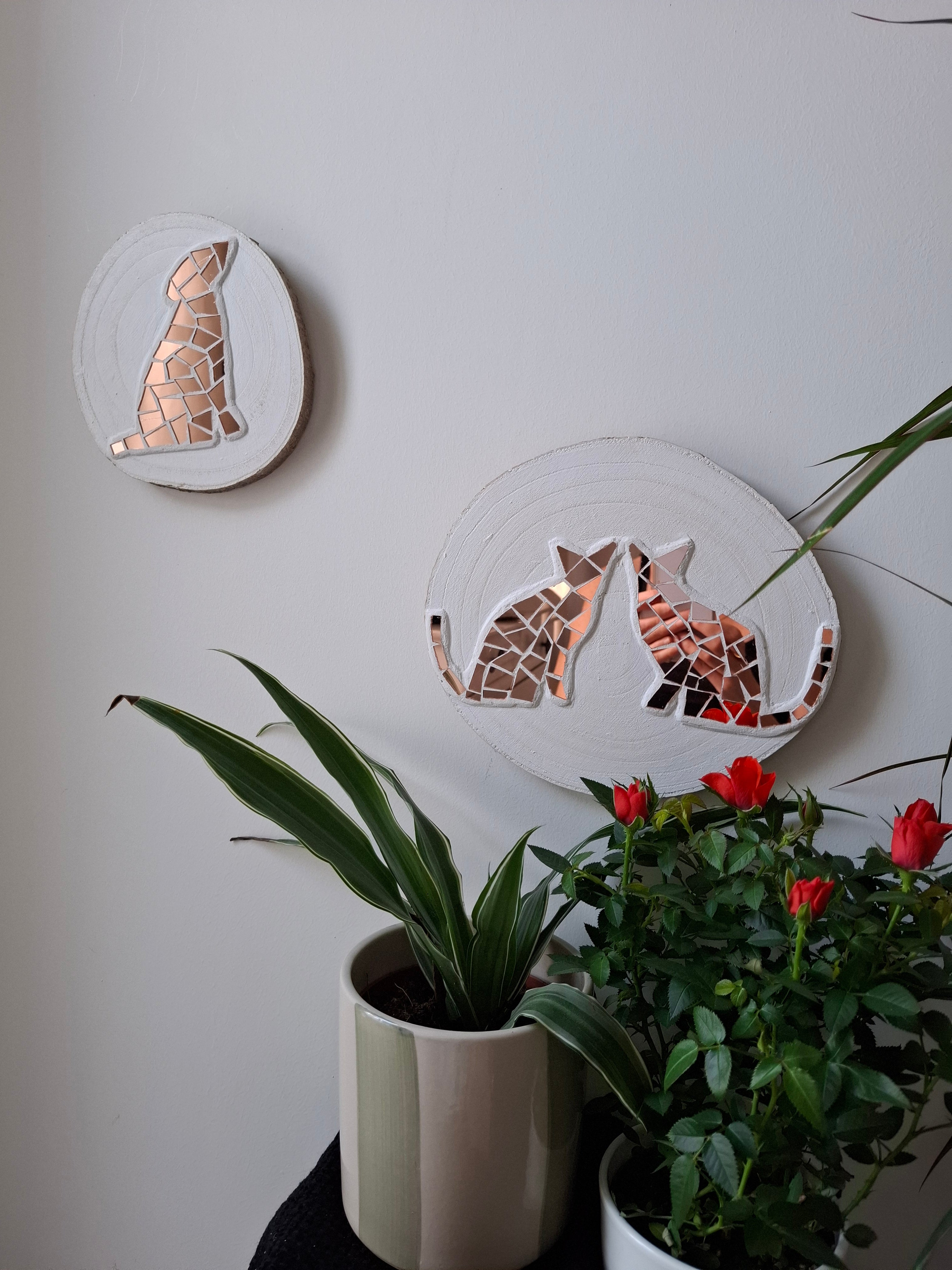 Cat and dog mosaics on the wall surrounded by plants