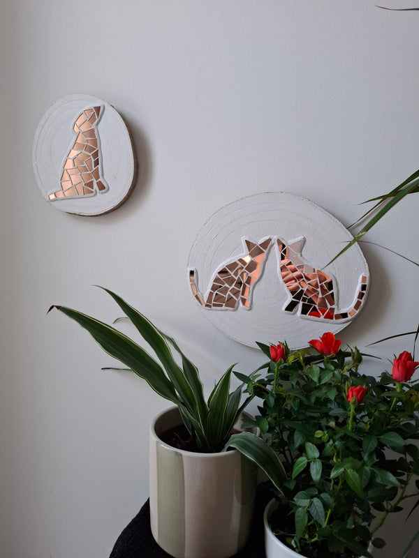 Cat and dog mosaics on the wall surrounded by plants
