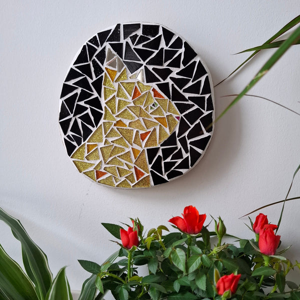Cat mosaic on the wall surrounded by plants
