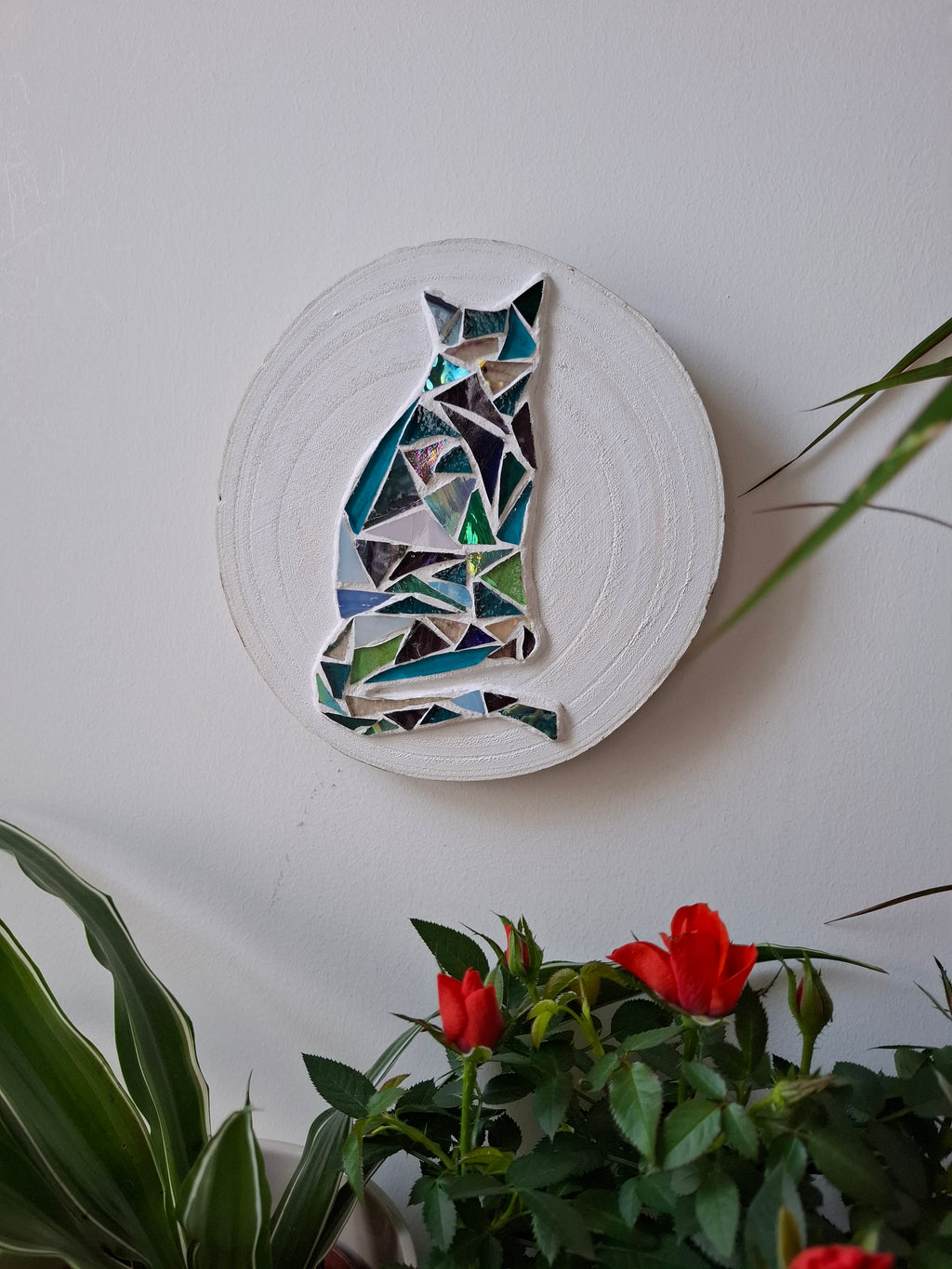 Cat mosaic on the wall surrounded by plants 