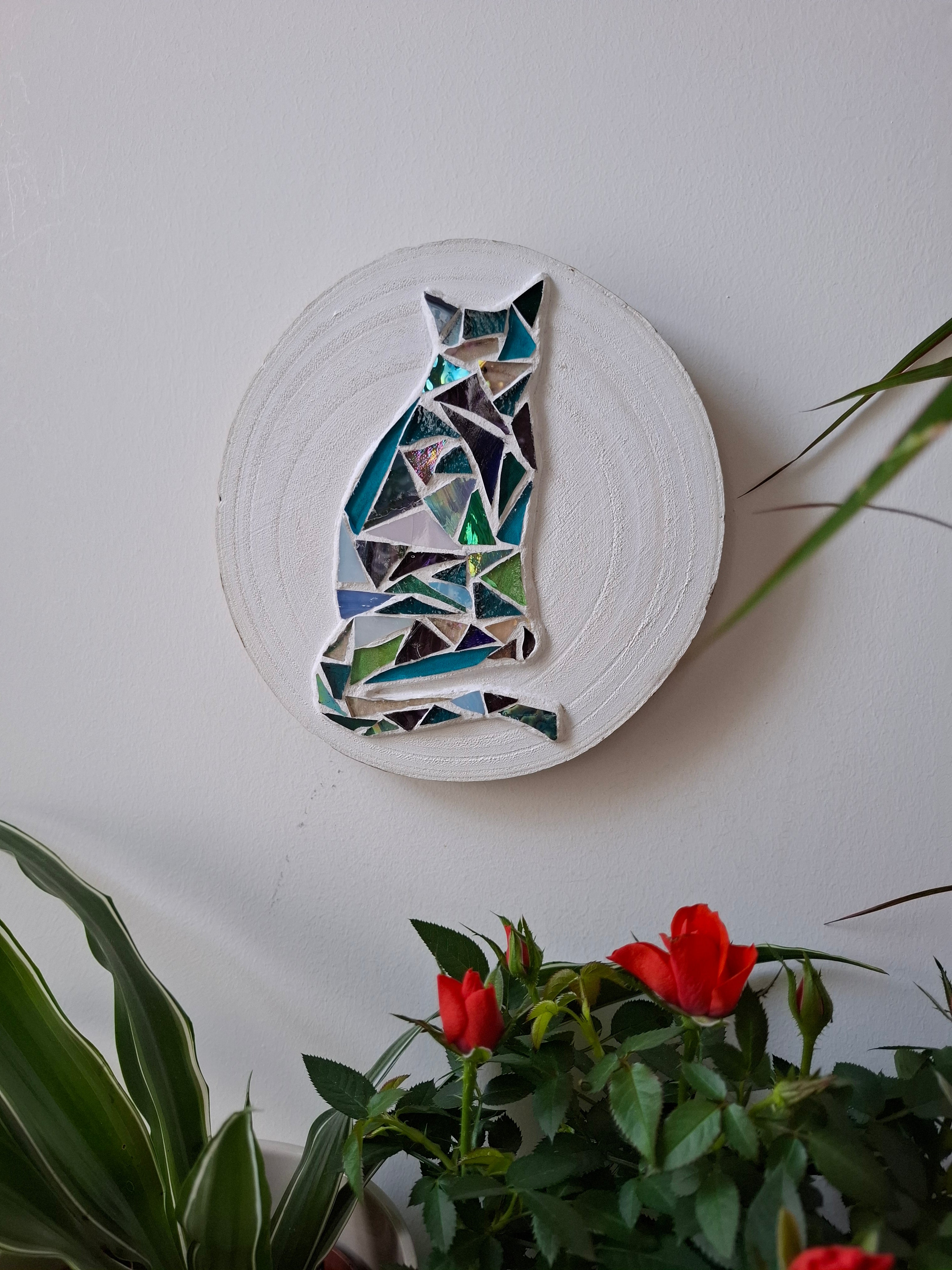 Cat mosaic on the wall surrounded by plants 