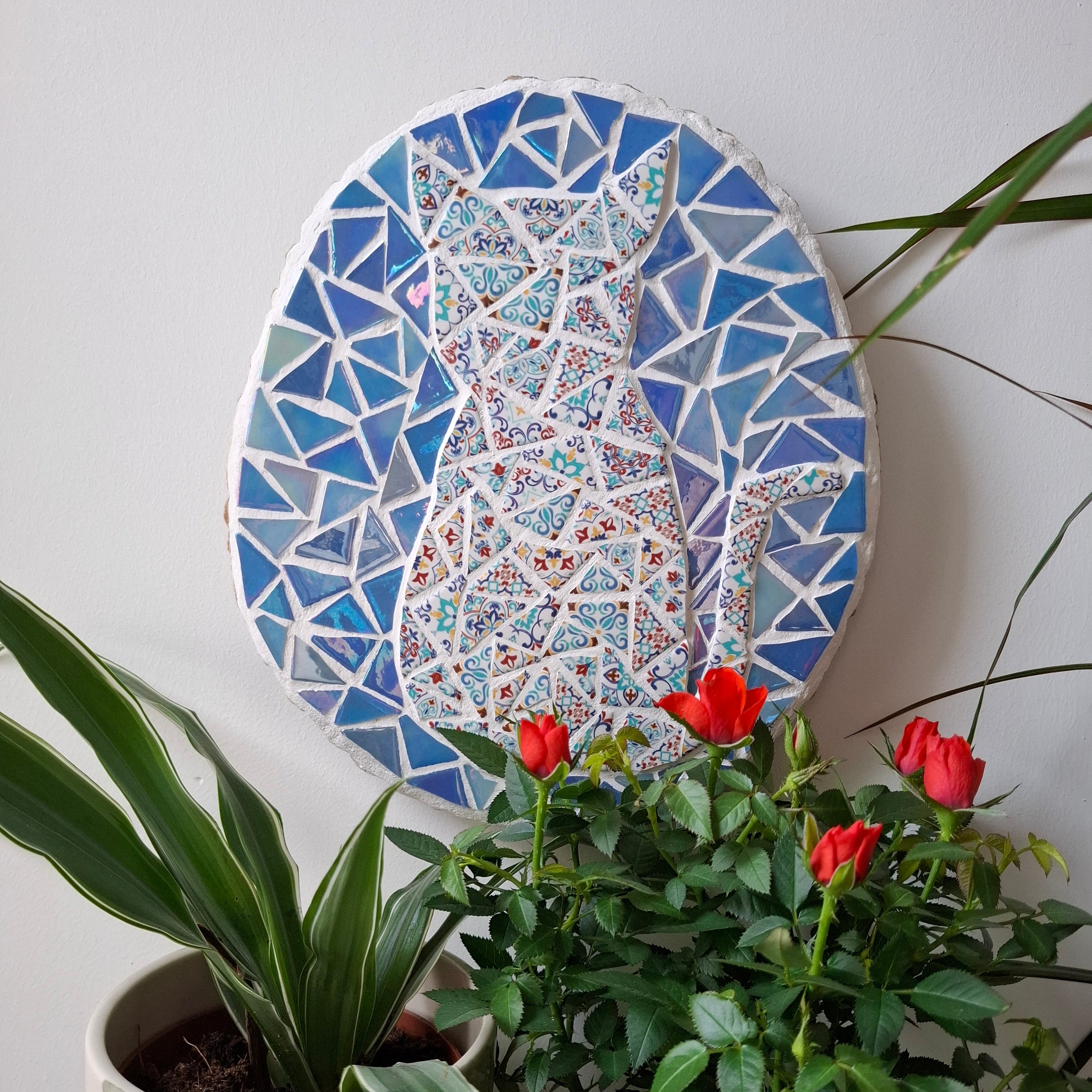 Cat mosaic on the wall surrounded by plants