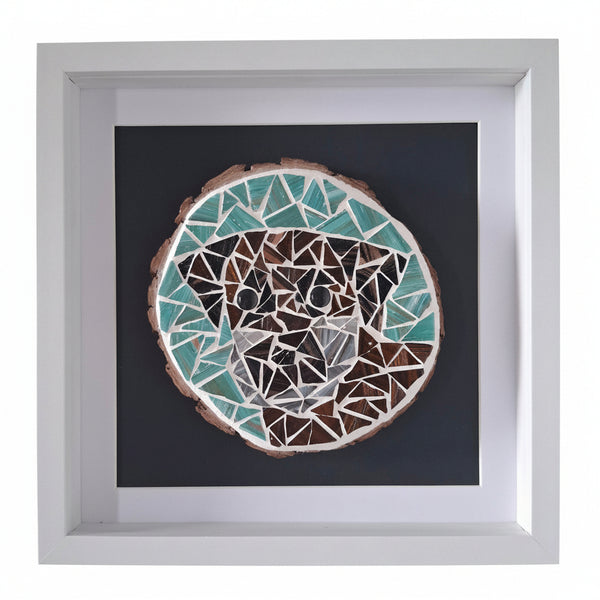 Framed mosaic art print featuring a stylized dog's face made of geometric shapes in teal, brown, white, and grey on a dark background, enclosed in a white frame.