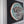 A circular mosaic wall art piece mounted on a dark square backing, framed in white. The artwork features a dog of teal, brown, grey, and white tiles