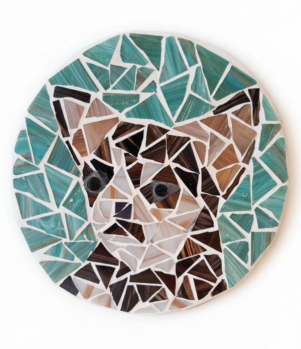 Circular mosaic wall art featuring a stylized dog design. Crafted with gold-dusted bronze and brown glass pieces on a gold-dusted aqua background, set on rustic wood.