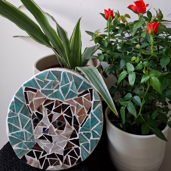 Dog mosaic on the table surrounded by plants

