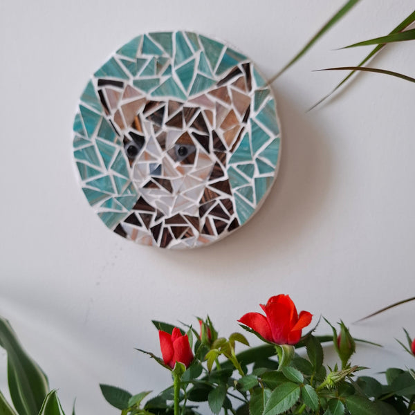 Dog mosaic on the wall surrounded by plants
