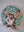 Side view of a circular dog mosaic artwork, showing the rustic wood edge.