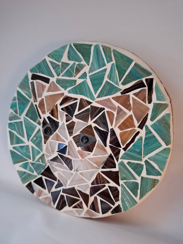 Side view of a circular dog mosaic artwork, showing the rustic wood edge.