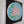 A circular mosaic wall art piece featuring a stylized flower in pink and green, set within a white frame with a black backing board.
