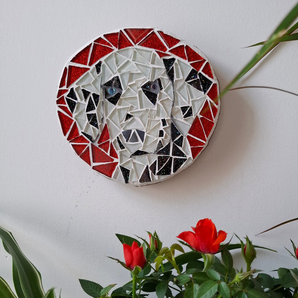 Dog mosaic on the wall surrounded by plants
