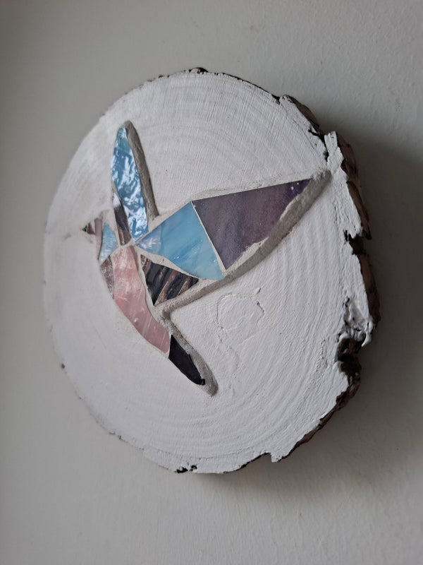 Side view of a circular dove mosaic artwork, showing the rustic wood edge.