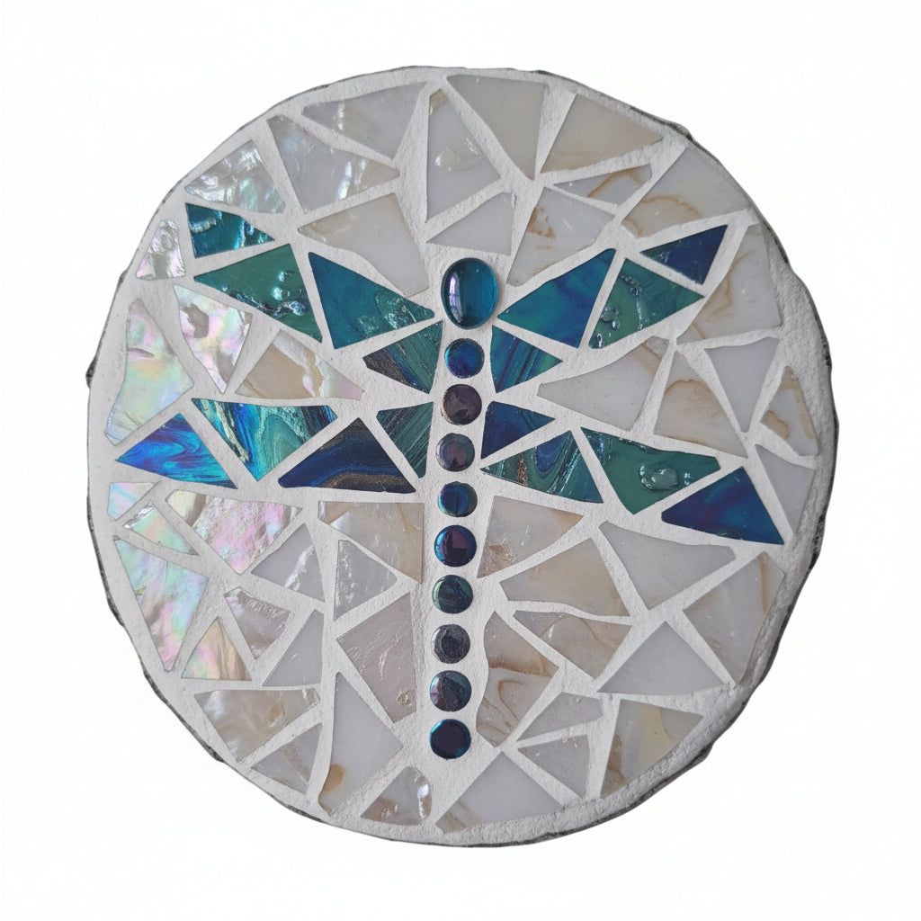 Circular mosaic wall art featuring a stylized dragonfly design. Crafted with gold-dusted dark blue glass pieces and iridescent gems on a gold-dusted white background, set on rustic wood.