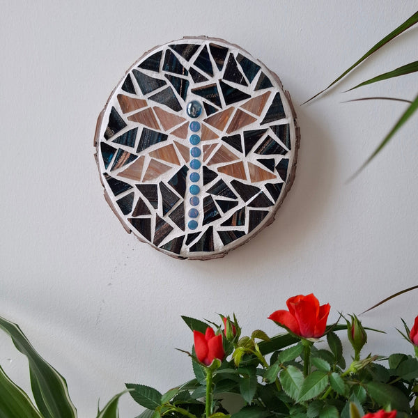 Dragonfly mosaic on the wall surrounded by plants
