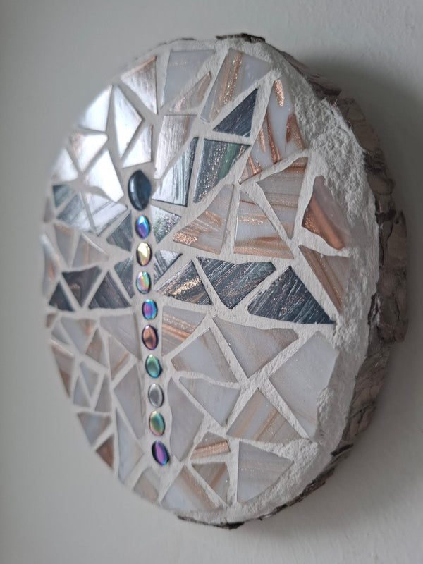 Side view of a circular dragonfly mosaic artwork, showing the rustic wood edge.